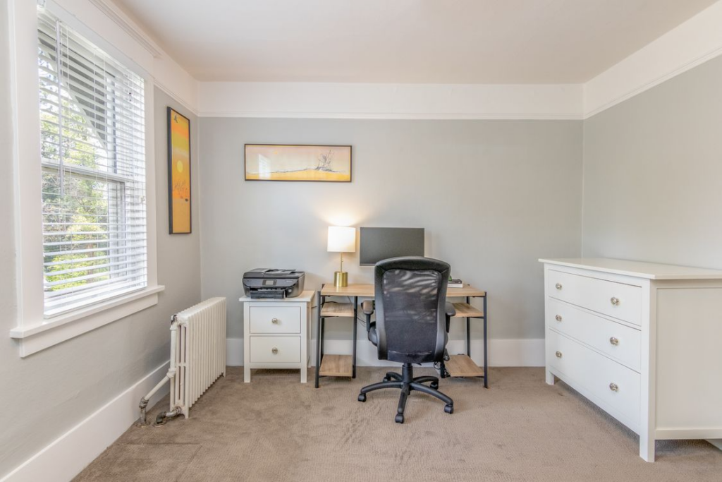 Home office with carpet flooring, desk, office chair, and natural light, showing a comfortable and practical workspace in a NZ home